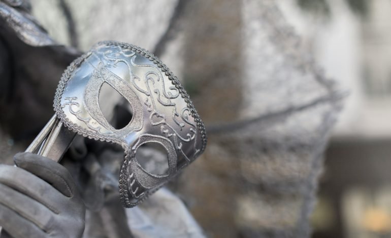A close-up of an ornate silver mask held by a gloved hand, symbolising the vibrant and diverse arts and culture scene in London. This image captures the essence of artistic expression and the intricate craftsmanship within the city, relevant to discussions about the future of arts and culture amid the upcoming general election.