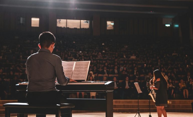 Musicians performing on stage with a large audience in the background, highlighting the importance of support for the arts in the UK