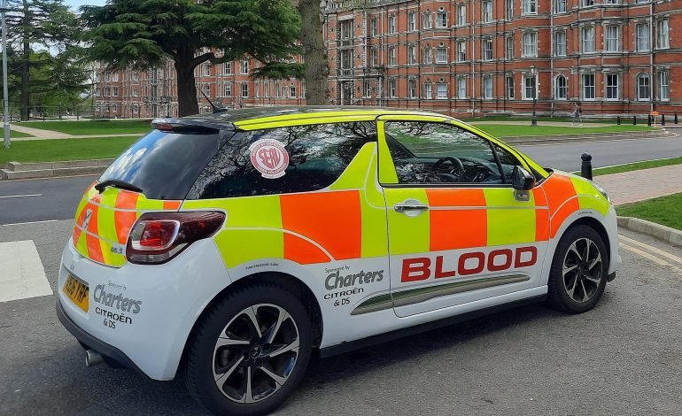 A car marked with bright yellow and orange reflective paint, with 'blood' written in clear writing on its side. Vehicles like this are used for safely transporting blood for use in medical facilities across the UK. The NHS has issued an Urgent Appeal for Blood Donors Following Recent Tech Issues.