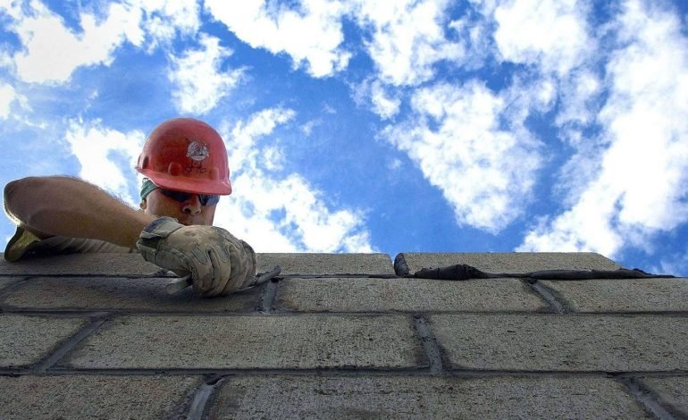 Construction worker laying bricks against a blue sky, representing Westminster Council's commitment to improving services with the new Leasehold Charter.
