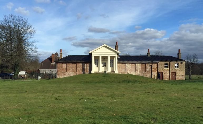 Wanstead Park's historic Temple building on a sunny day with green lawns and a clear blue sky.