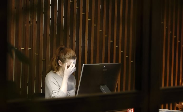 Person experiencing stress while working at a computer, highlighting the importance of somatic exercise for mental and physical health.