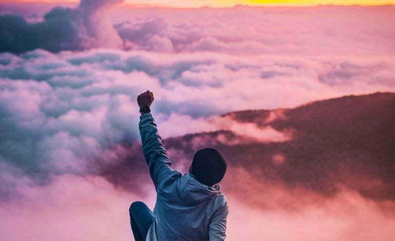 A person celebrating on a mountaintop at sunrise, symbolising the power and revitalising effects of ancient adaptogens on mind and body.