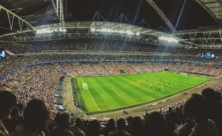 A packed Wembley Stadium during a night match, with the crowd eagerly watching an England football game. The image captures the excitement and anticipation of the fans, reflecting the national football spirit. Lee Carsley, set to potentially lead the England team in upcoming Nations League matches, aims to inspire similar scenes of support and enthusiasm.