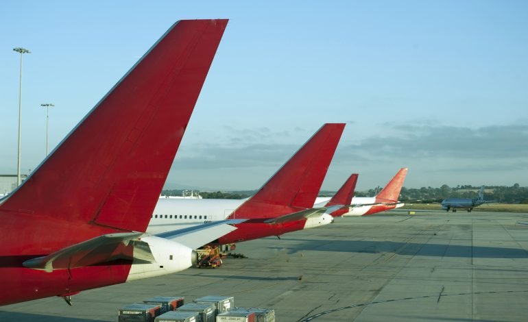 Middle East flight suspensions and airline service disruptions with parked airplanes on airport tarmac.