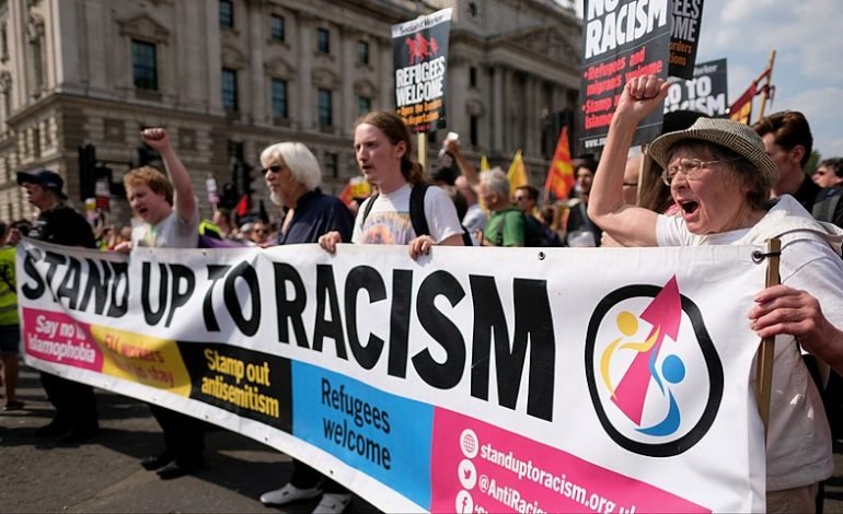 Anti-racism protesters in London hold banners calling for justice and unity in response to recent unrest.
