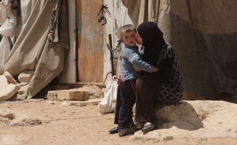 A mother and child in Lebanon, sitting outside a shelter, embody the impact of recent Hezbollah communication device explosions.