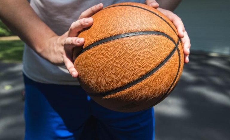 A young basketball player holding a basketball, symbolising the start of the West London Gators and their new season at Hammersmith Academy.