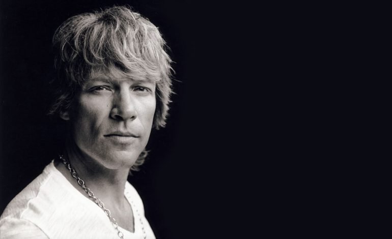 Black and white portrait of Jon Bon Jovi, musician and actor, looking directly at the camera with a serious expression.