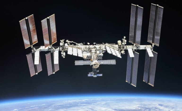 Boeing’s Starliner and the International Space Station orbiting above Earth with solar panels.