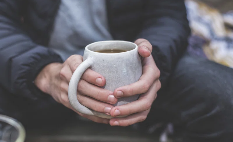 Person holding a warm cup, reflecting the impact of winter fuel payment cuts on pensioners in the UK.
