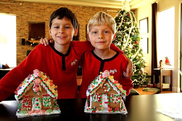 Brothers decorating gingerbread houses together at Christmas.