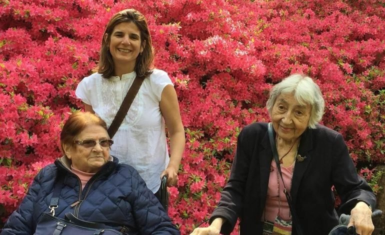 Patients receiving assistance from Dispensaire Français staff in Hammersmith, surrounded by colourful pink flowers.