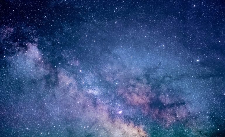 A deep space image representing dark energy, showing a vast expanse of stars and cosmic dust in shades of blue and purple.
