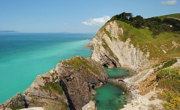 Scenic cliffside view along the King Charles III England Coast Path, showcasing turquoise waters and rugged terrain