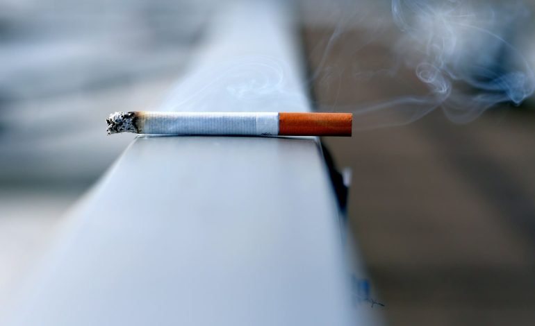 cigarette burning on ledge for article on smoking rates