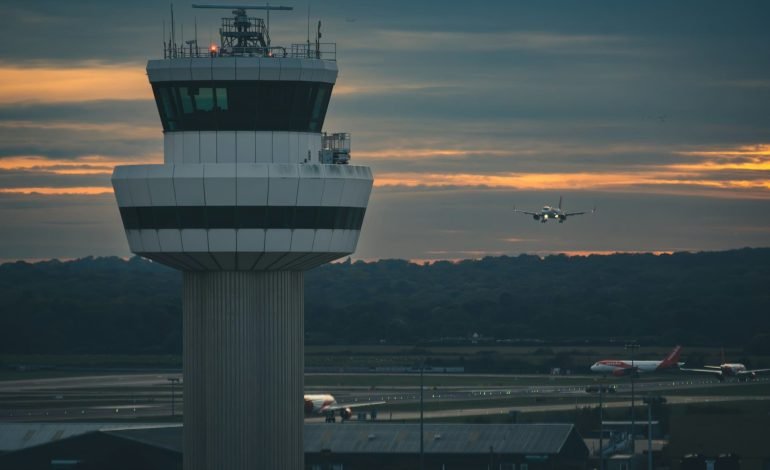 Air traffic control tower with an EasyJet plane ready for landing as it approaches the runway at Gatwick airport around dusk