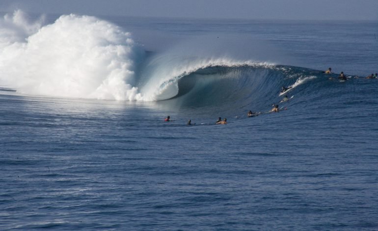 Ocean wave with surfers near shore, reflecting the natural setting of the SeaCURE carbon removal project