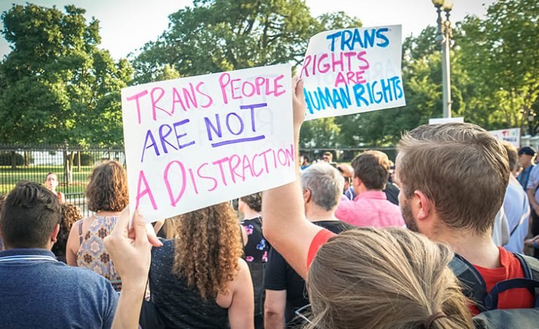 Protesters hold signs supporting trans rights during a public demonstration related to UK Supreme Court legal definition ruling