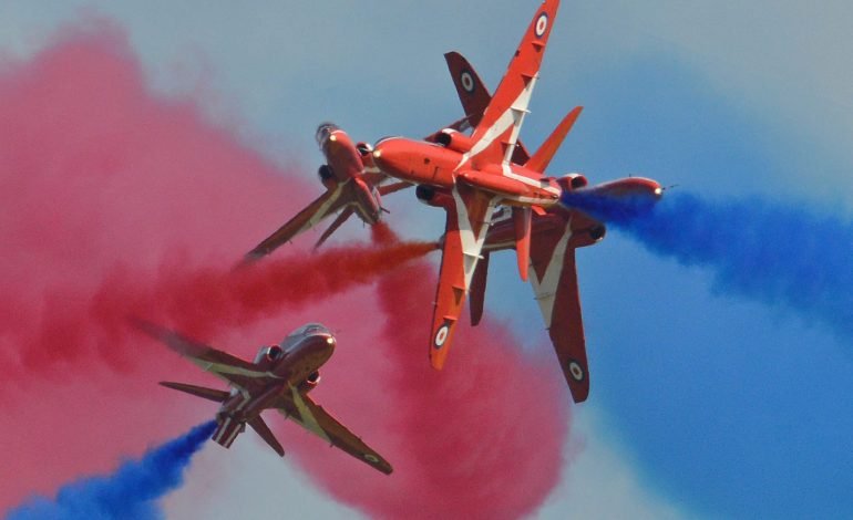 Red Arrows flypast in blue sky during VE Day 80th anniversary celebrations