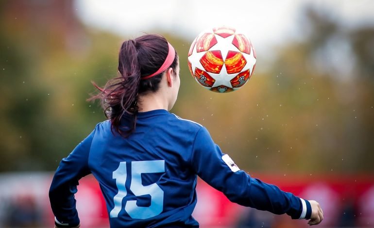 Young women with eyes focused on the soccer ball while controlling it during a girl football match