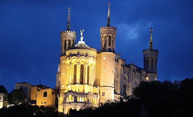 Basilica of Notre Dame de Fourvière illuminated at night in Lyon, seen while cruising the River Rhône