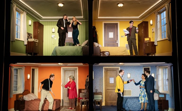 Cast of The Comedy About Spies performing in a split level hotel room set on stage at the Noel Coward Theatre