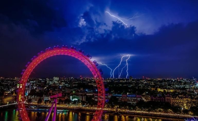 London Eye lightning storm over city skyline during summer heatwave weather warning.