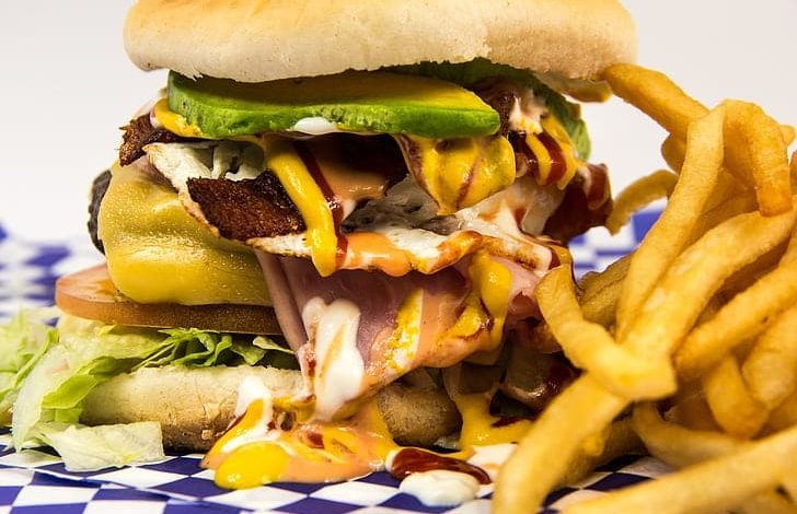 GP Mounjaro concerns highlighted by a close up of a high calorie cheeseburger with fries, illustrating lifestyle related obesity issues