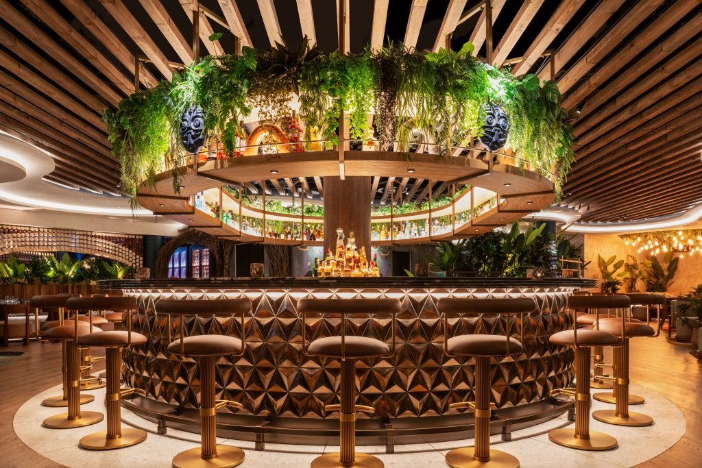 Los Mochis redefines rooftop bar design – a circular centrepiece framed by warm wood, rich textures, and an overhead canopy of greenery.