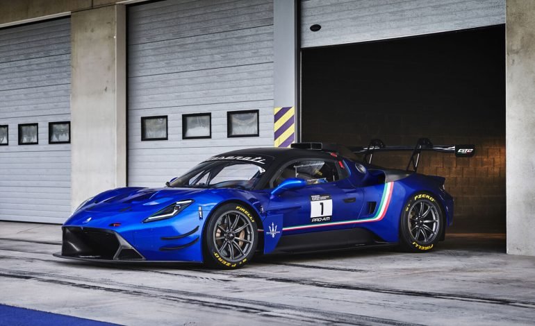 a blue maserati gt2 race car exiting a garage in the pit lane