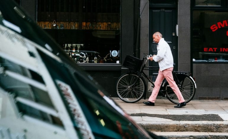 man walking bicycle along pavement