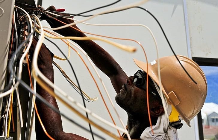 Electrician conducting safety checks on housing wiring for overdue inspections