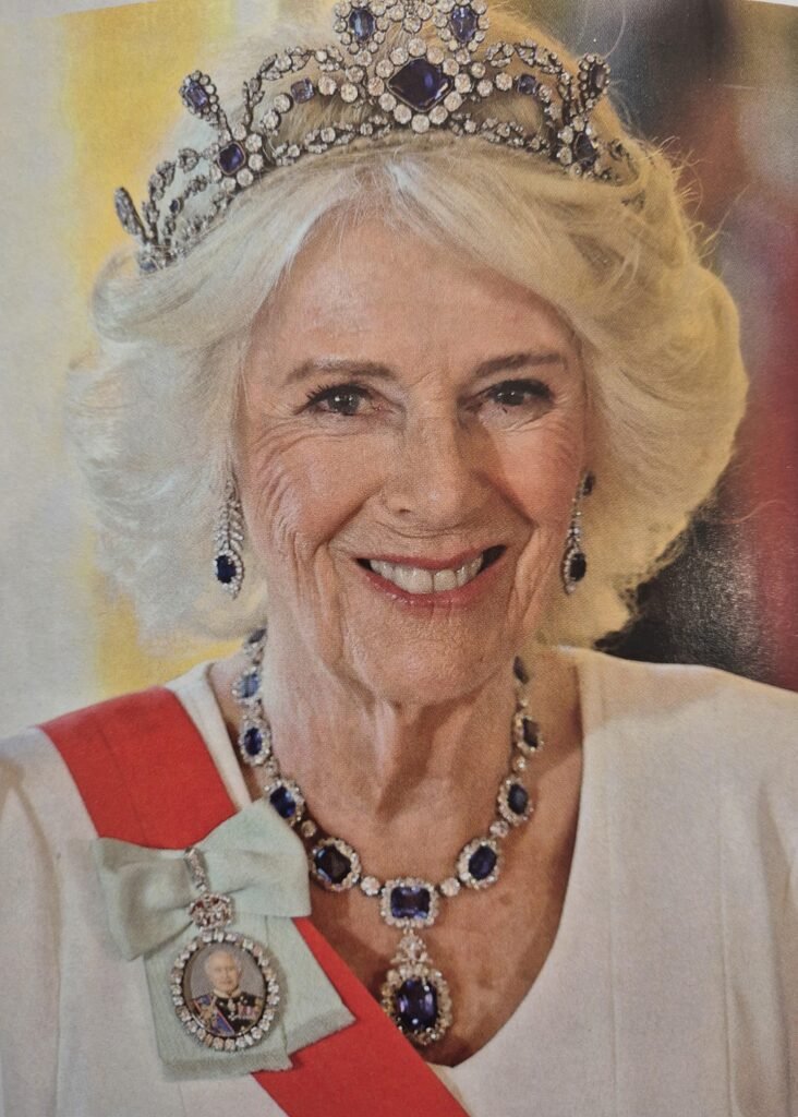 Queen Camilla wearing tiara, sapphire necklace and King Charles III miniature portrait Family Order at state banquet