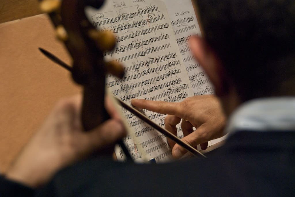 Musician reviewing classical music sheet during rehearsal for September classical CD reviews