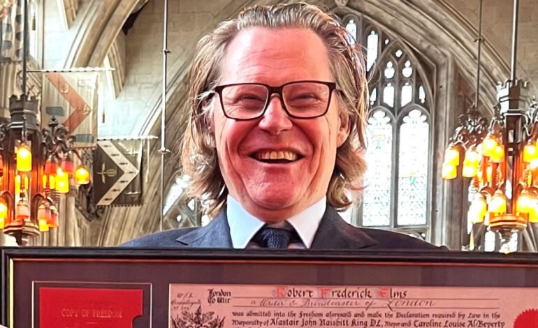 Robert Elms honoured at Guildhall holding his Freedom certificate inside Guildhall, City of London