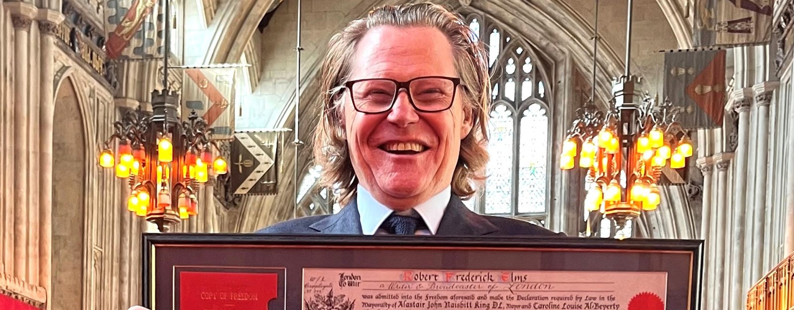 Robert Elms honoured at Guildhall holding his Freedom certificate inside Guildhall, City of London