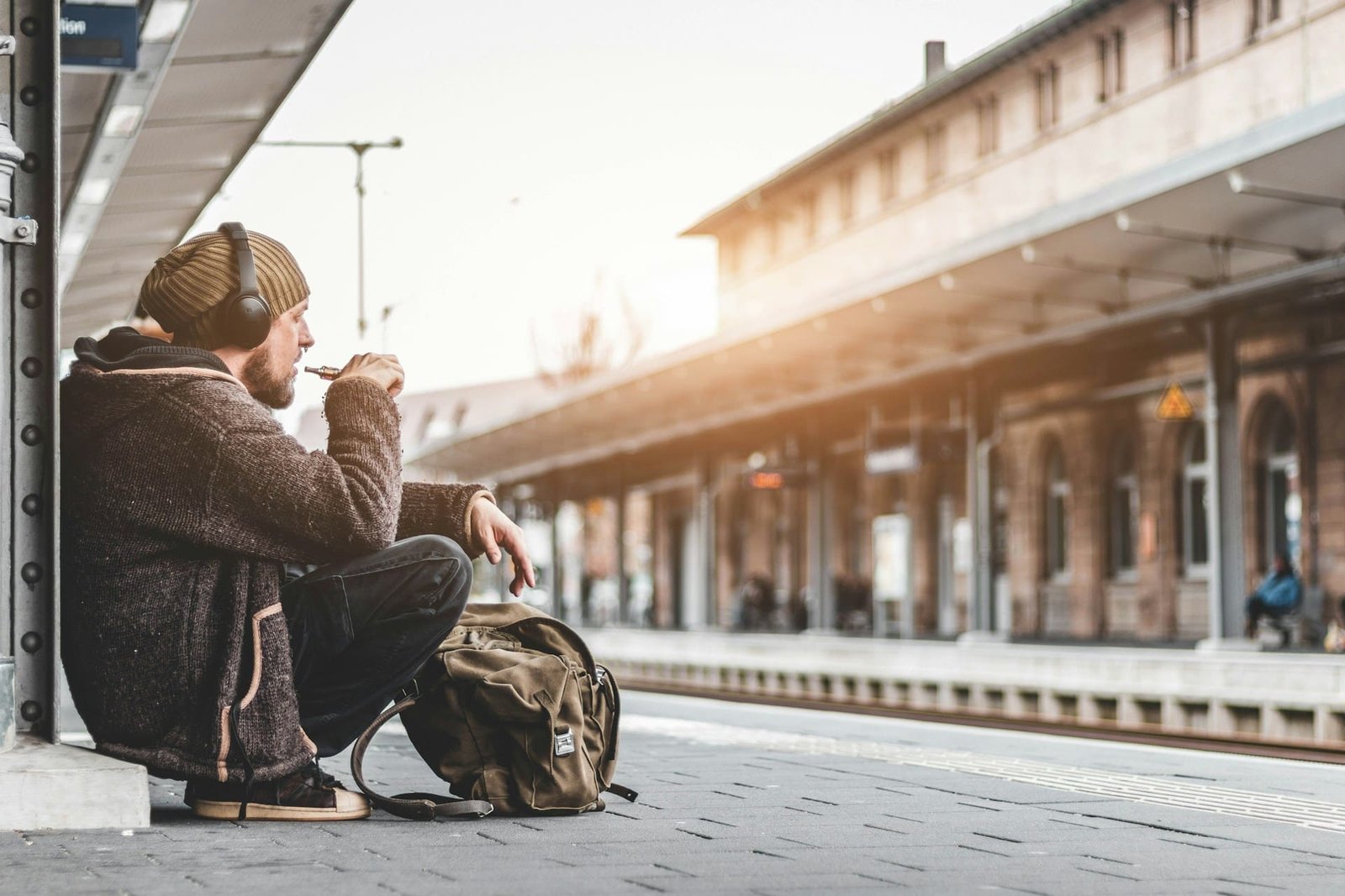 man sitting on train platform with headphones
