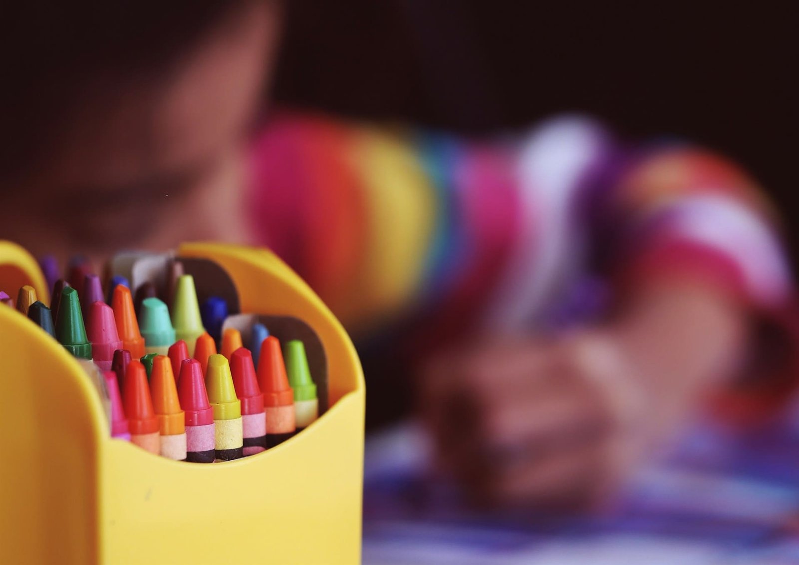 stack of crayons with blurry child in the background