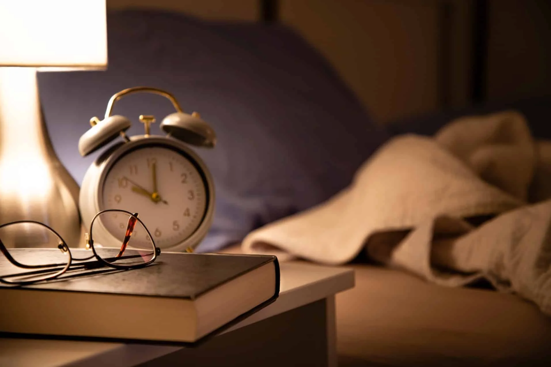 Alarm clock and bedside table at night symbolising the clocks going back and sleep patterns during daylight saving time.