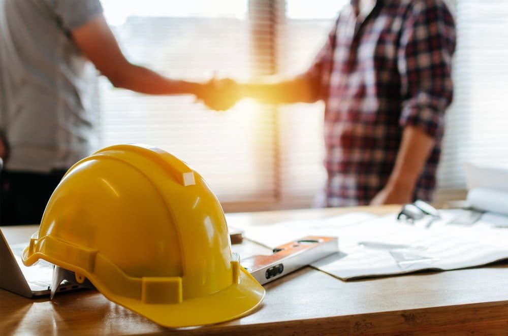 HMRC labour supply chain rules for construction contractors, yellow hard hat and handshake in office setting