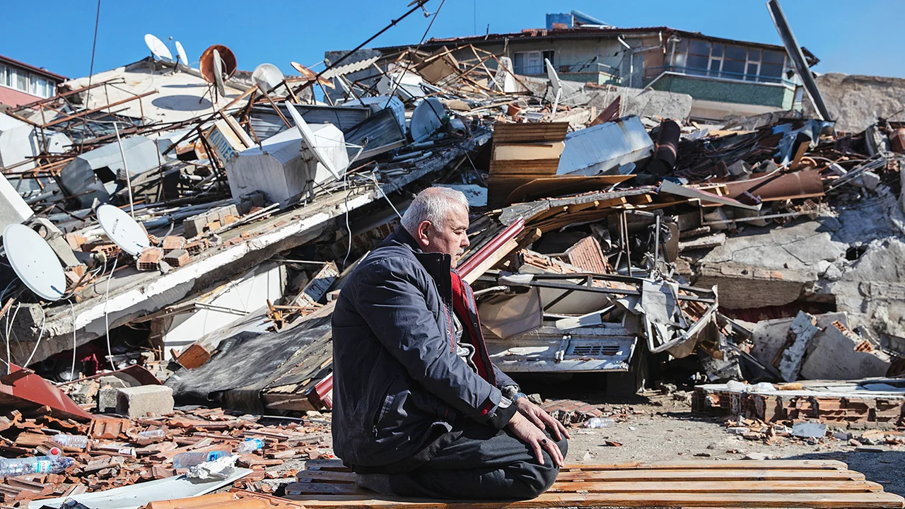 Man sitting amid rubble of collapsed buildings after the Balikesir earthquake in western Turkey.