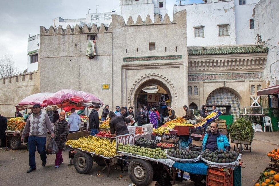 The bustling medina of Tetouan — where historic gates open onto vibrant market stalls filled with fresh produce, reflecting centuries of cultural exchange and everyday life.