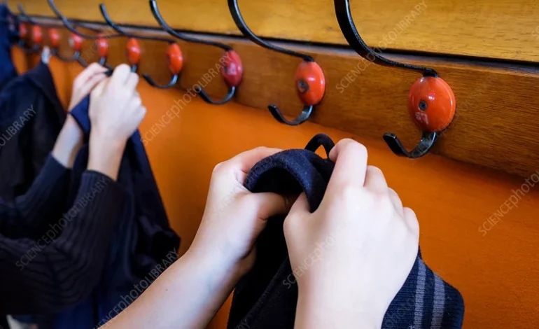 Children hanging coats on school hooks in a primary school linked to unlawful arrest case involving parents’ complaints