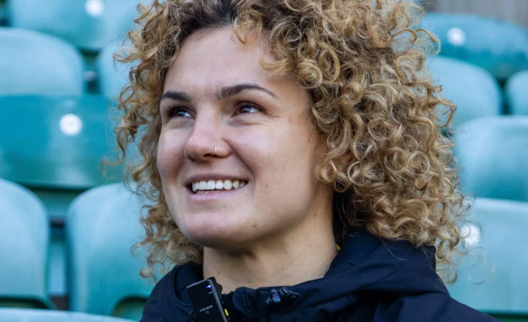 Ellie Kildunne smiling in the stands ahead of her role as the Christmas Voice of Heathrow.