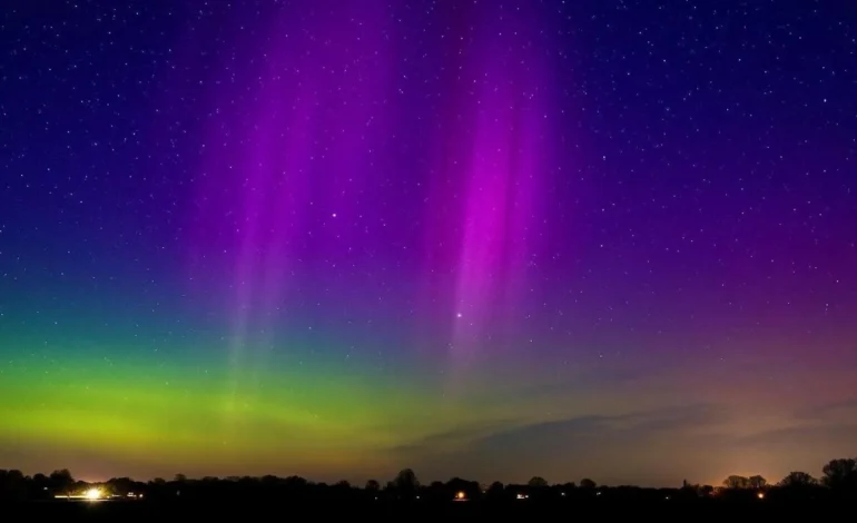 Northern Lights UK glowing in purple and green above a rural skyline under clear night skies.