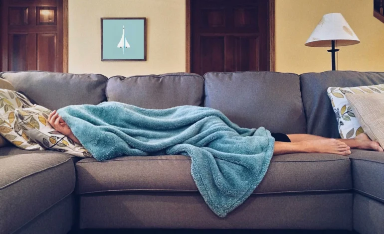 Person off sick at home under a blue blanket, symbolising the need for a workplace health overhaul to keep Britain working.