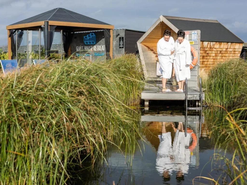 Guests beside the natural swimming pond at the Glass House Wellness Retreat