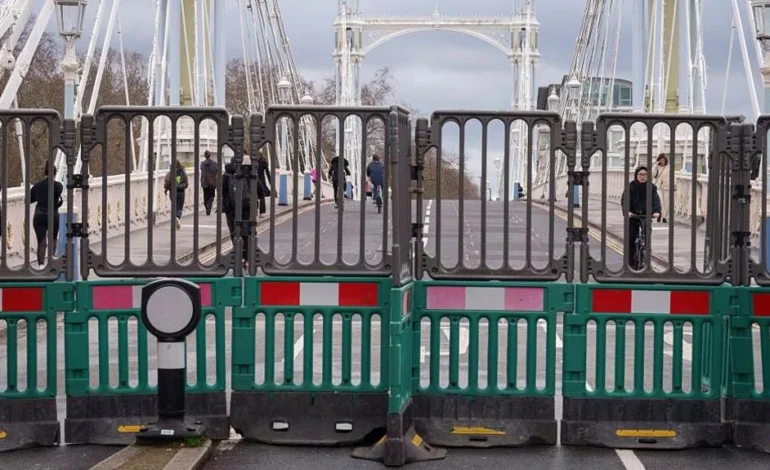 Barriers blocking vehicles on Albert Bridge closed to traffic while pedestrians continue crossing
