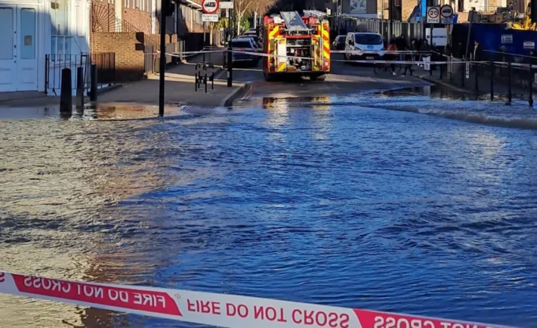 Flooded Caledonian Road after water main burst in Islington with emergency crews on scene